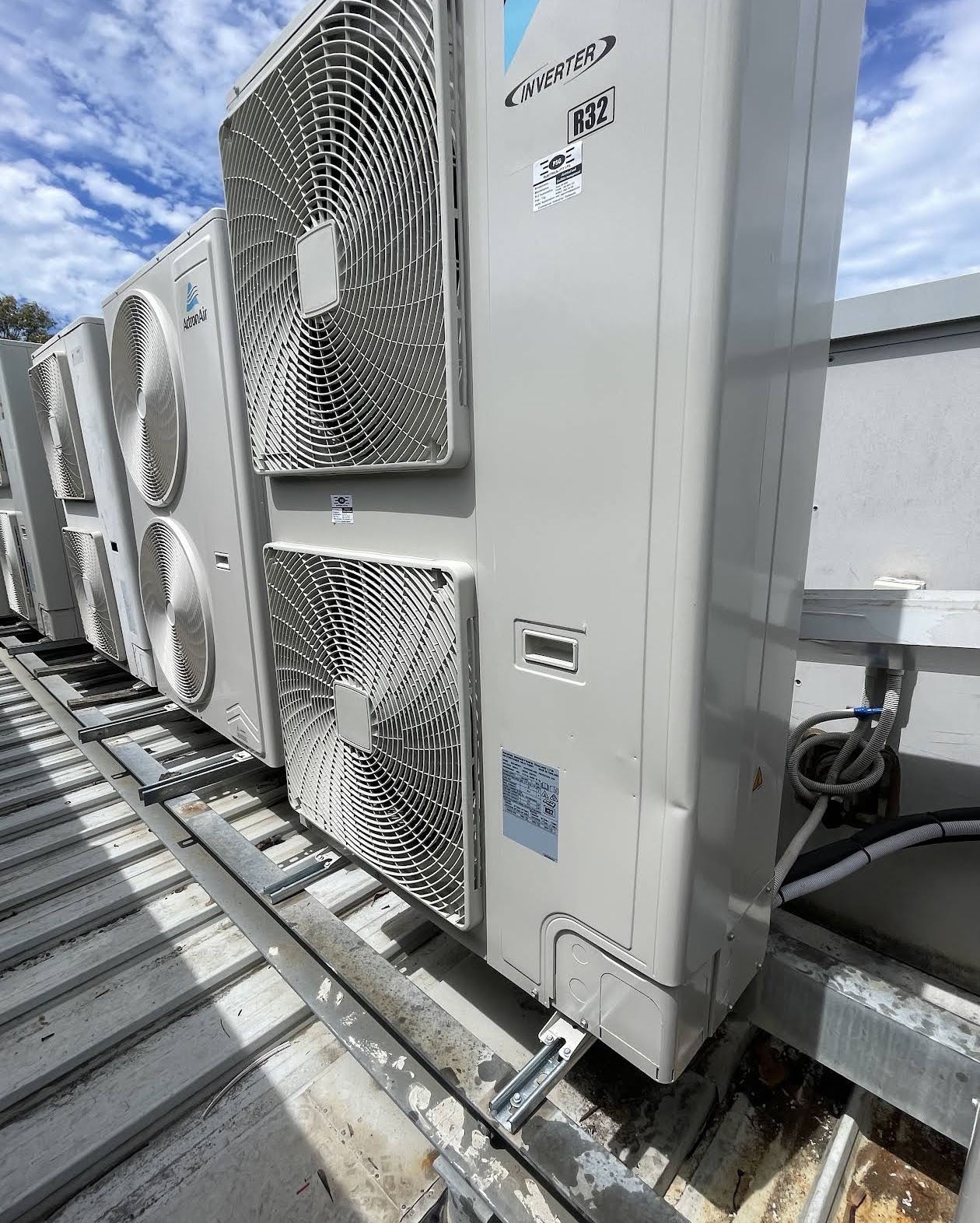 Row of commercial inverter air conditioning condensers on a metal rooftop