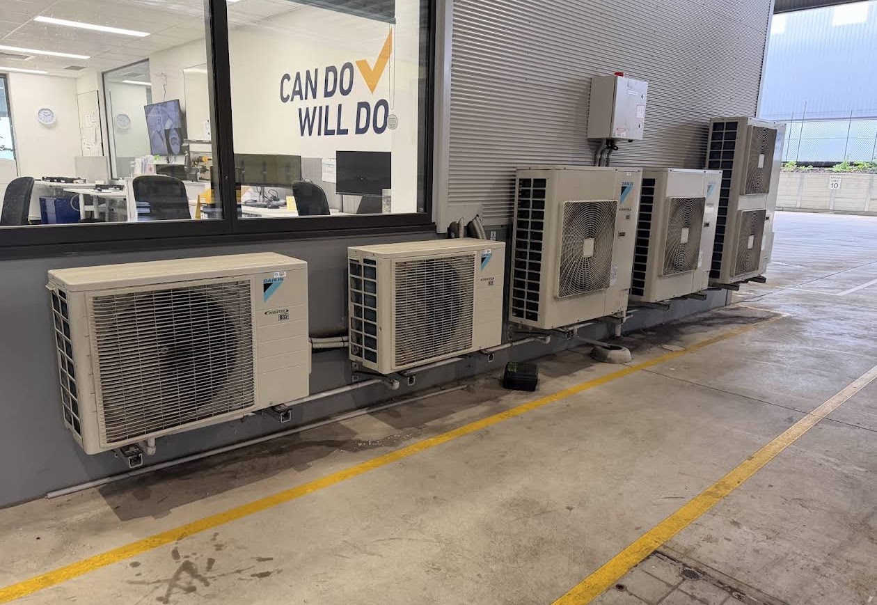 Five Daikin air conditioning condensers installed in a row along a commercial building wall